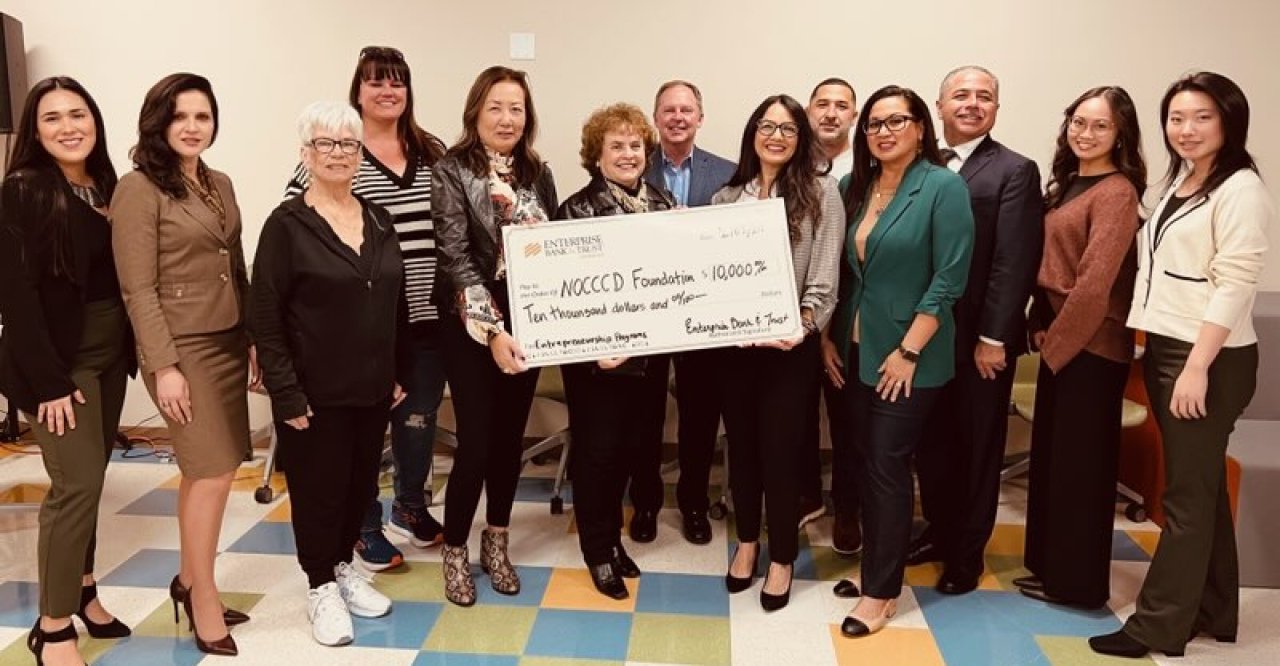 Dr. Cathleen Greiner holds large check with representatives from NOCCCD and Enterprise Bank & Trust