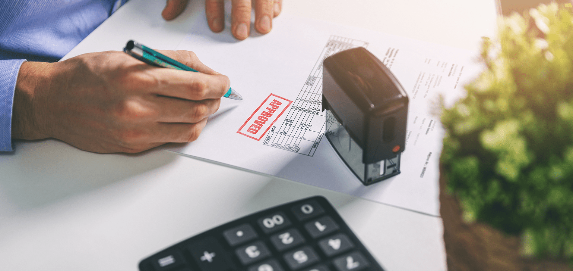 person at desk with stamp and calculator approving a form