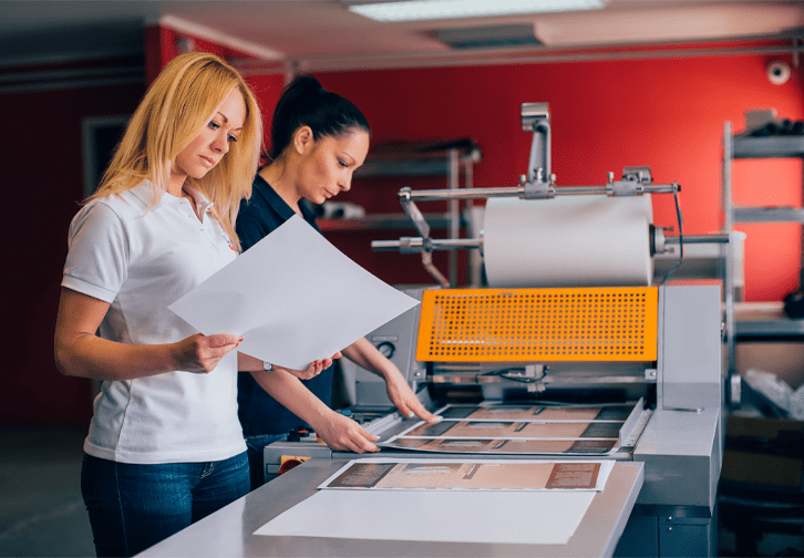 two people inspect large printing job