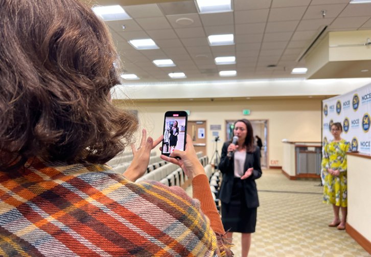 Natalie Rubalcava with microphone while being filmed 