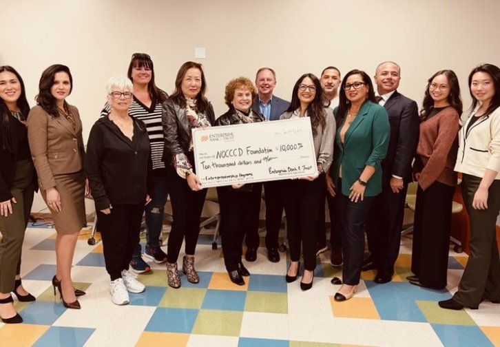 Dr. Cathleen Greiner holds large check with representatives from NOCCCD and Enterprise Bank & Trust