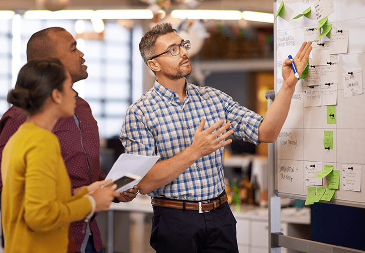 three people looking at a board working together