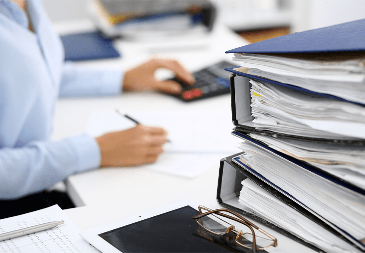 person working at desk with binders stacked on table