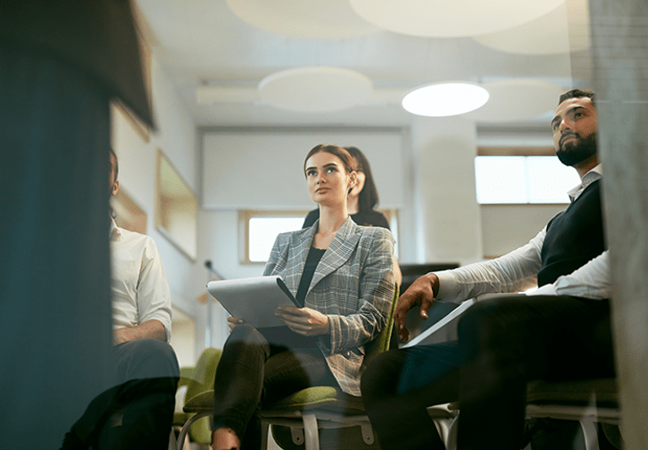 people dressed in business clothes sitting down watching a presentation