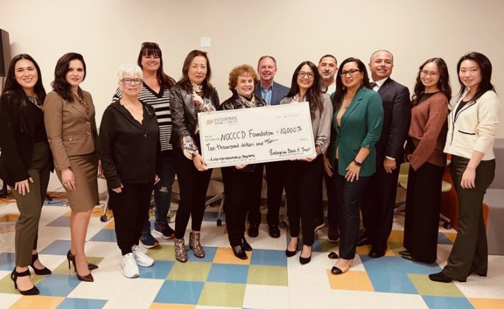 Dr. Cathleen Greiner holds large check with representatives from NOCCCD and Enterprise Bank & Trust