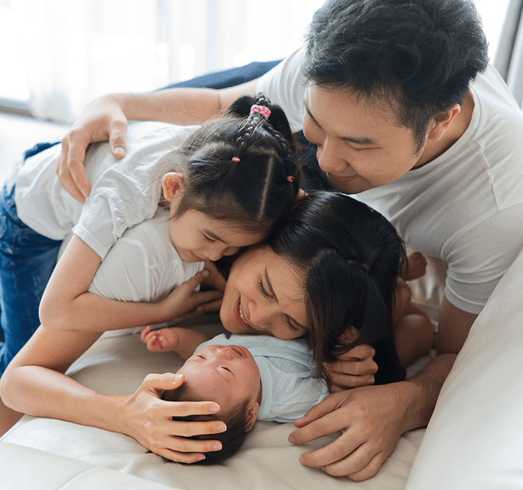 Mom, dad, daughter snuggling a newborn baby