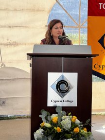 2024 Board President Evangelina Rosales speaks at a podium at Cypress College