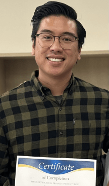 man smiling and holding up a Certificate