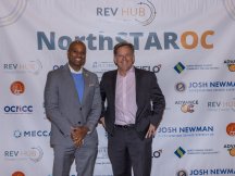 two men in suits in front of NorthStarOC banner