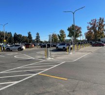 A parking lot with a car in the distance using an electric vehicle charging station