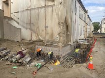 exterior of a building with plastic sheeting on the sides and rebar stacked beside it